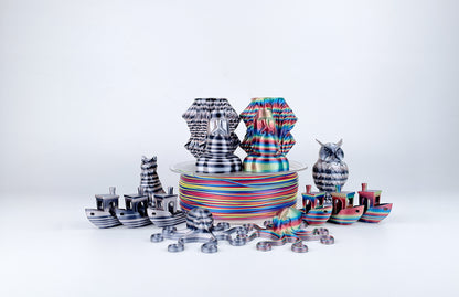 EIBOS Artism Series II Ribbons PLA filament with striped multicolour and black-and-white 3D prints, including boats, owls, octopuses and decorative models.