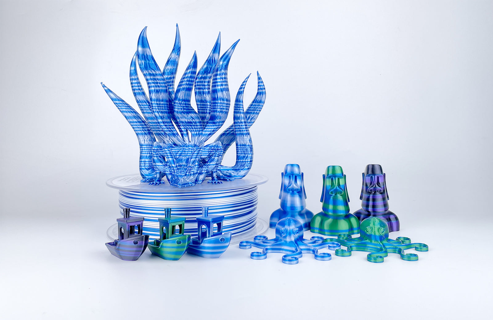 EIBOS Artism Series II Ribbons PLA filament with striped 3D prints, including a nine-tailed fox, Moai statues, Benchy boats and octopuses.