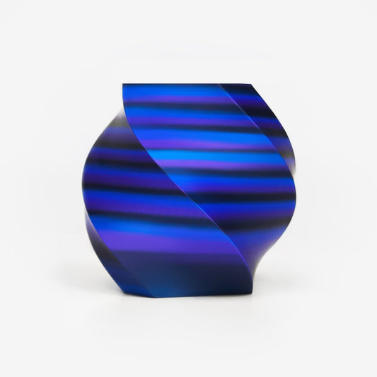 Twisted vase 3D printed with EIBOS Artism Series II Ribbons PLA in black, blue and purple, showing its glossy striped colour effect.