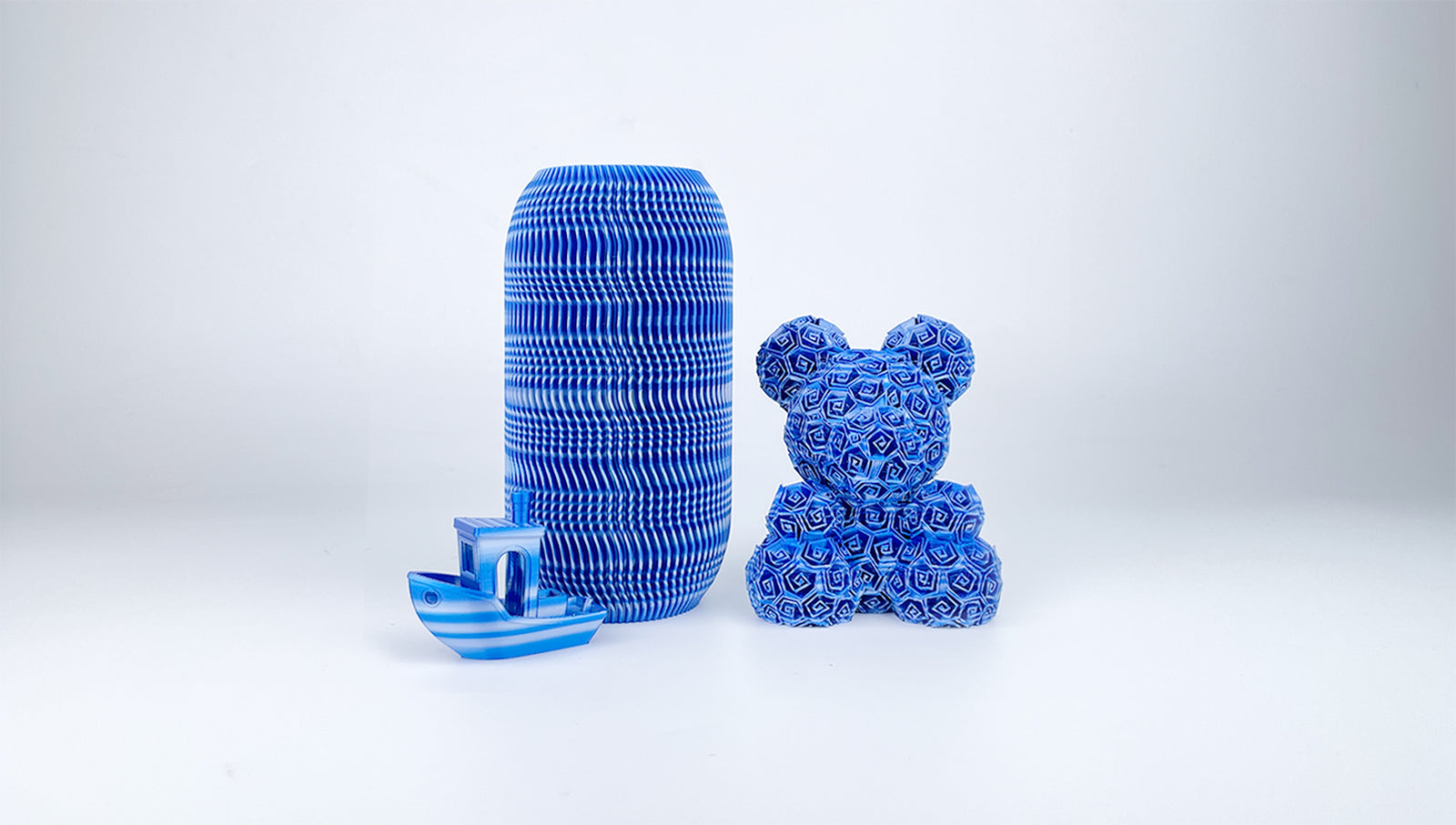 Blue, silver and white vase, teddy bear and Benchy boat 3D printed with EIBOS Artism Series II Ribbons PLA filament.