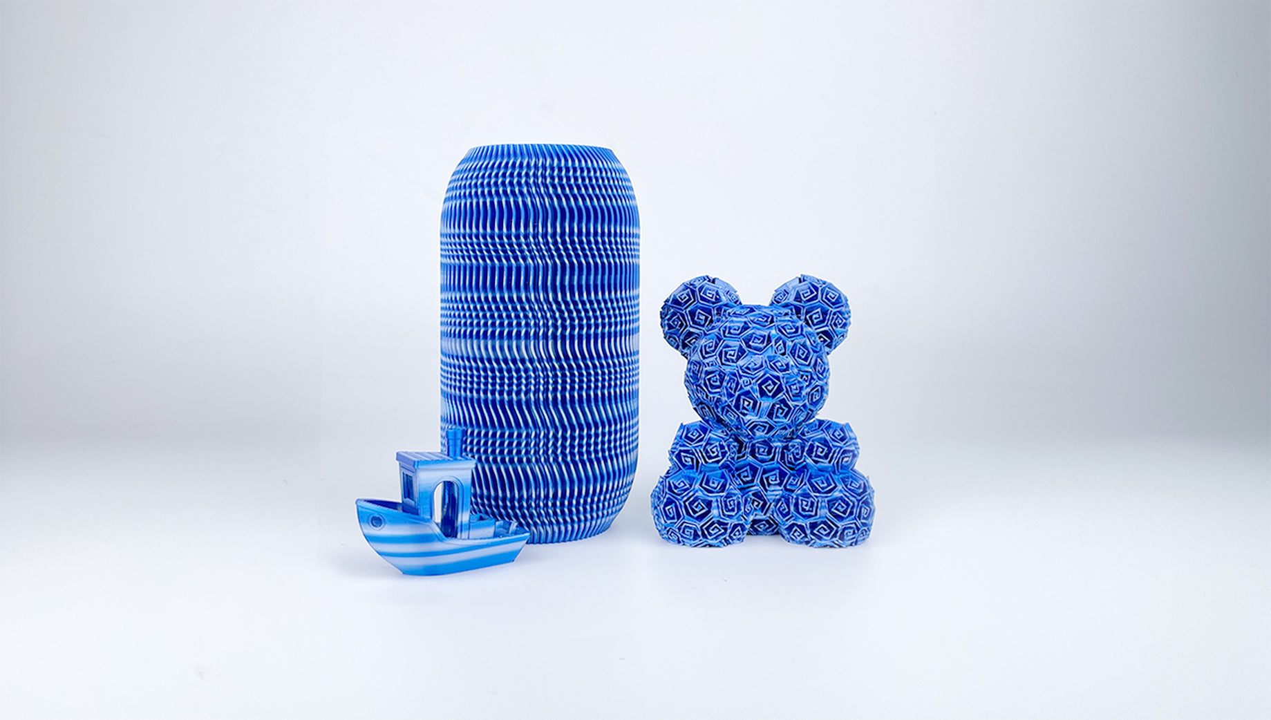 Blue, silver and white vase, teddy bear and Benchy boat 3D printed with EIBOS Artism Series II Ribbons PLA filament.