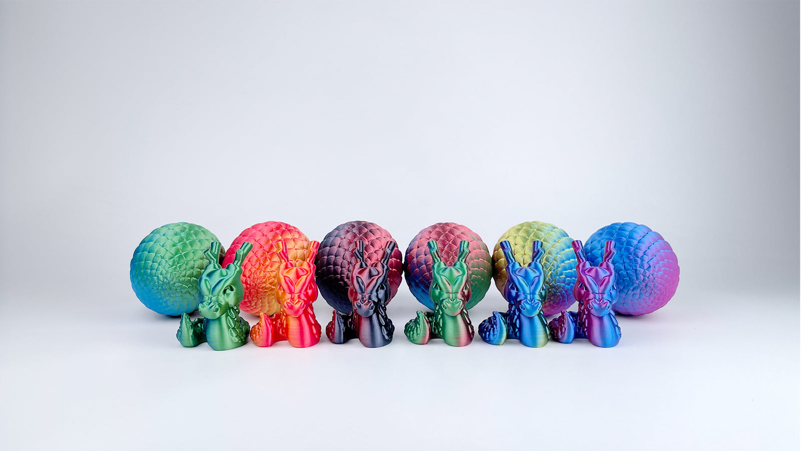 Colourful dragon models and textured eggs 3D printed with EIBOS Silk Series PLA filament in multiple silk colour combinations.