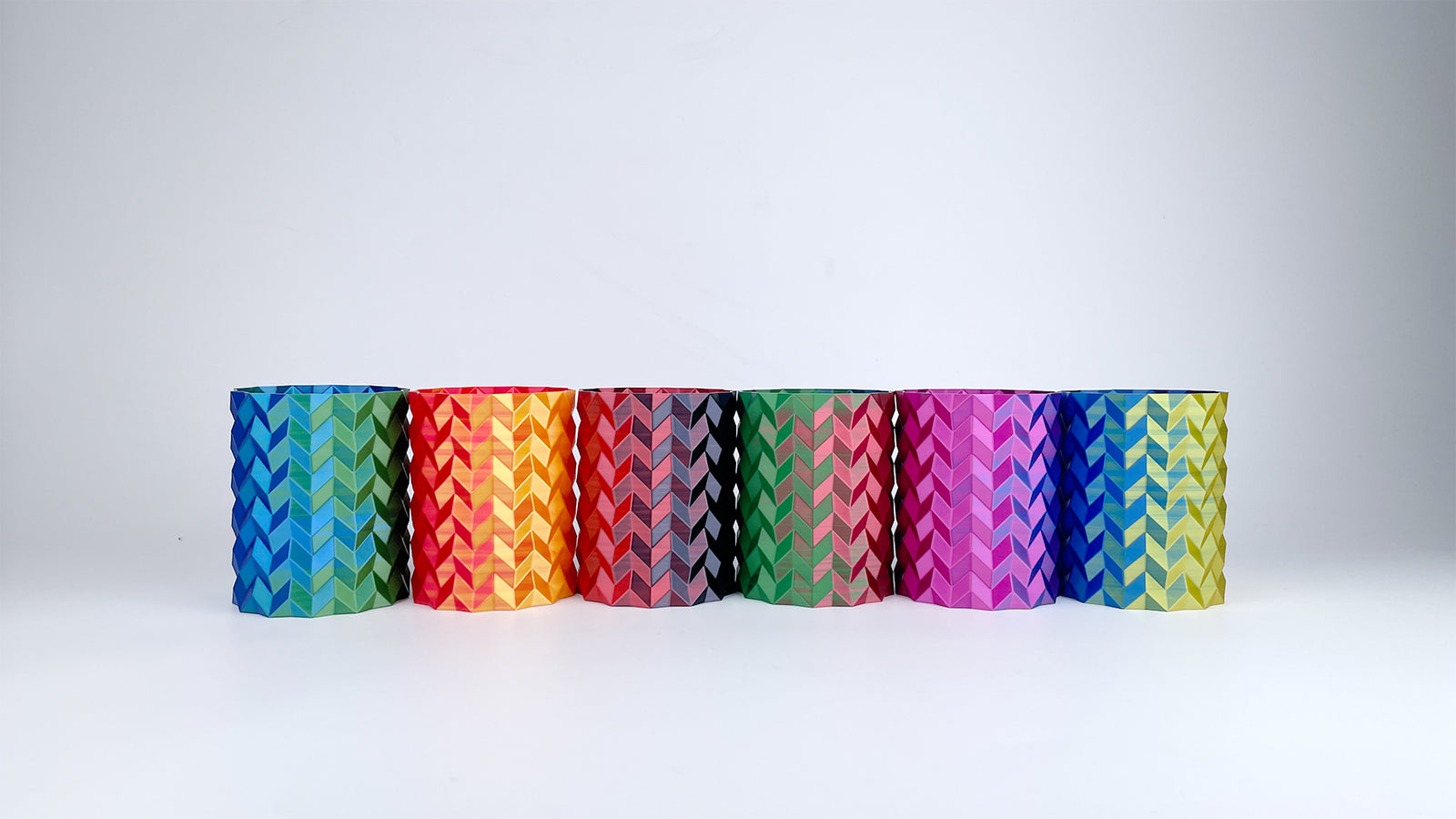 Six Multicolour geometric vases 3D printed with EIBOS Silk Series PLA filament, showing vibrant dual- and tri-colour silk finishes.